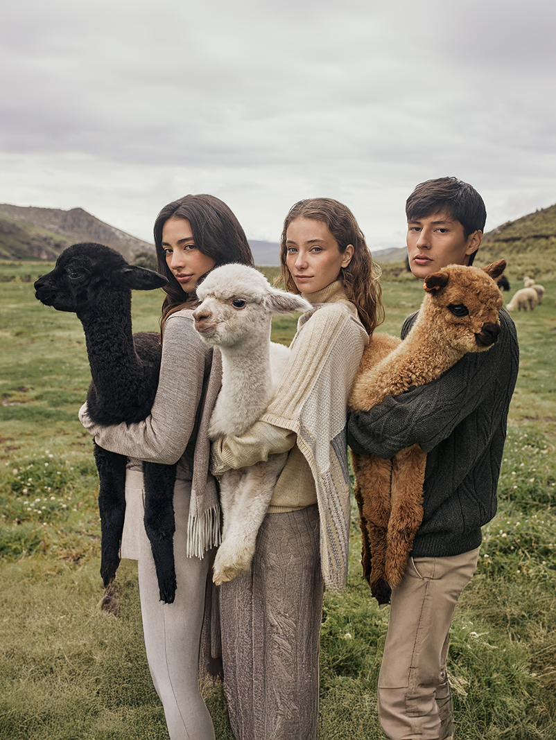 Modelos con prendas de inspiración andina junto a alpacas, destacando la fibra de alpaca en moda sostenible